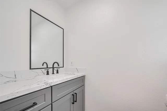 a bathroom with a granite countertop sink and a mirror