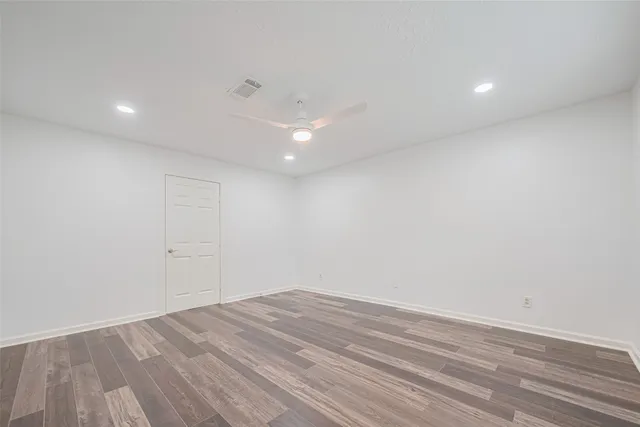 an empty room with wooden floor and white walls
