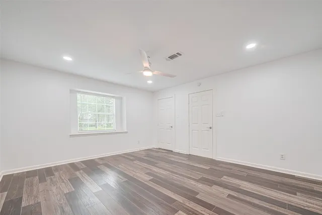 an empty room with wooden floor and windows