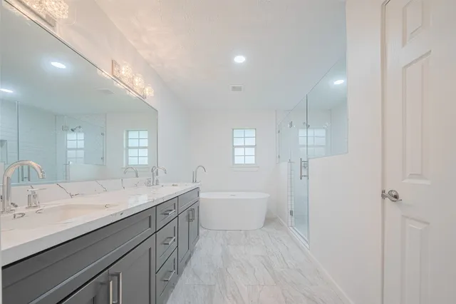 a bathroom with a double vanity sink a mirror and a bathtub