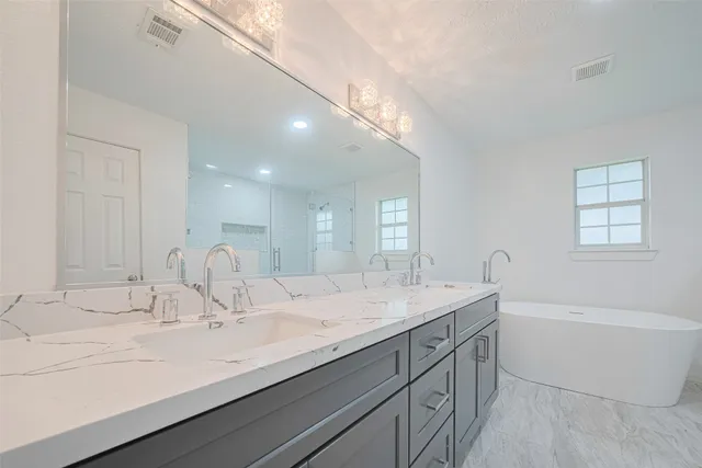 a bathroom with a double vanity sink a mirror and bathtub