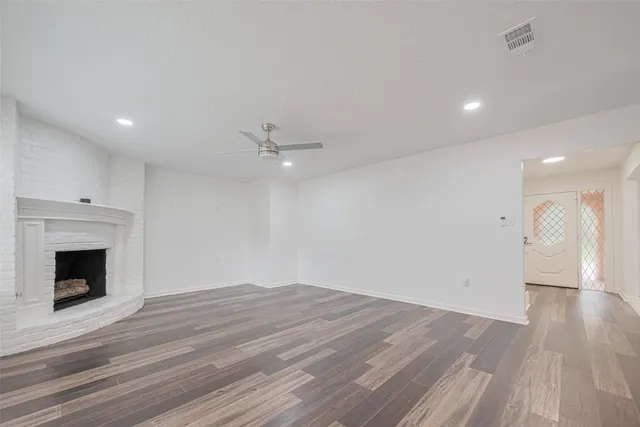 a view of empty room with wooden floor and fireplace