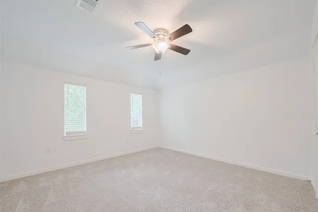 an empty room with window and a ceiling fan