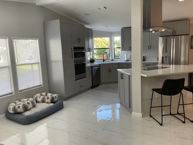 a kitchen with stainless steel appliances kitchen island granite countertop a refrigerator and a sink