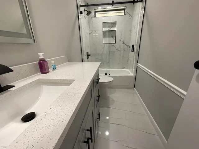 a bathroom with a granite countertop sink a toilet and shower