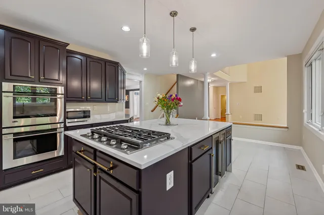 a kitchen with kitchen island granite countertop stainless steel appliances a stove cabinets and wooden floor