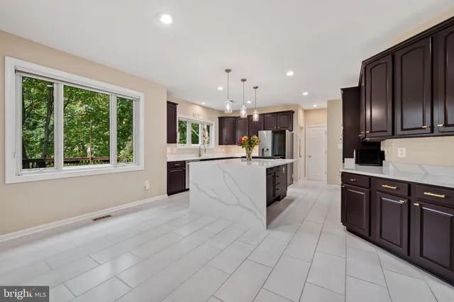 a large kitchen with kitchen island granite countertop a large counter top stainless steel appliances a sink a stove and cabinets