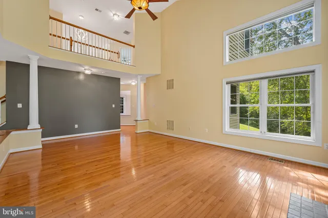 a view of an empty room with window and wooden floor