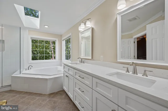 a bathroom with a tub double sink window and mirror