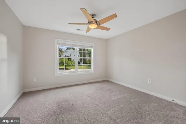 an empty room with a ceiling fan and window