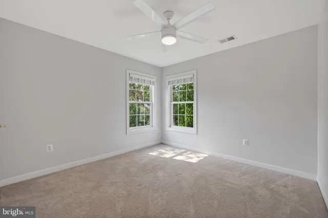 an empty room with windows and ceiling fan