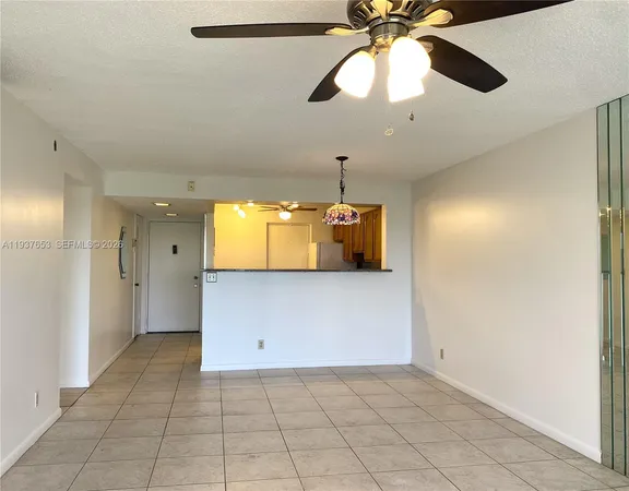 a view of a livingroom with a chandelier fan and kitchen space