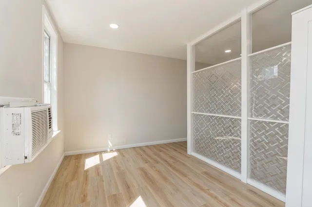 an empty room with wooden floor and windows