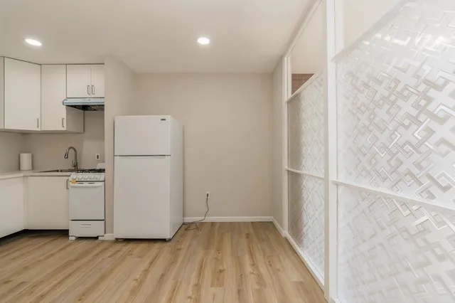 a kitchen with stainless steel appliances white cabinets and wooden floor