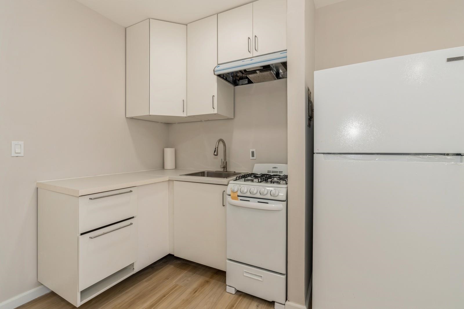 40 Beacon Avenue, Unit 5 Jersey City, NJ 07306 - Photo 18 of 20 a kitchen with stainless steel appliances white cabinets and wooden floor