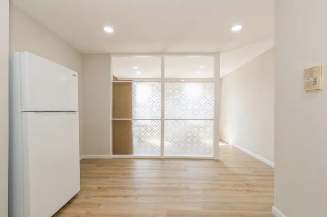 a view of an empty room with wooden floor and a window
