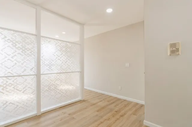 a view of an empty room with wooden floor and a window