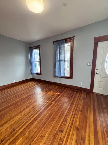 a view of an empty room with wooden floor and window