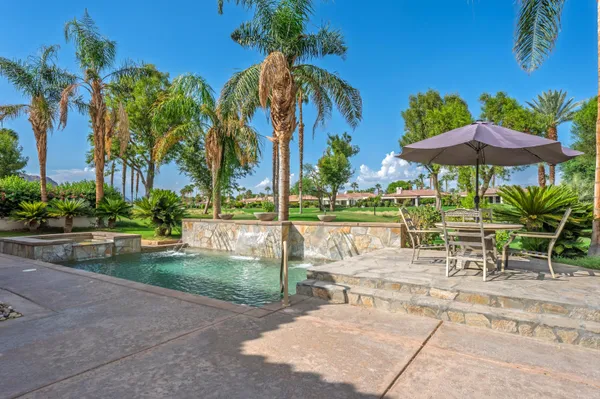 a kitchen with stainless steel appliances granite countertop a sink a stove a refrigerator cabinets and a dining table with wooden floor