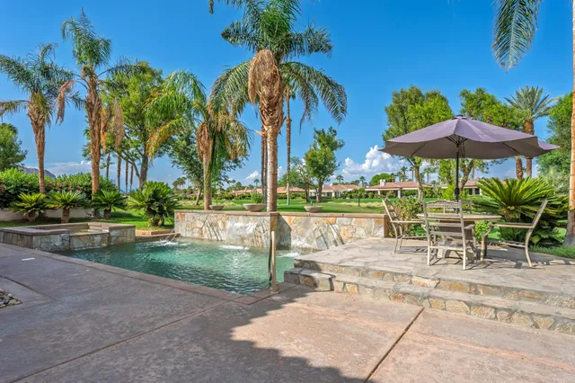 a kitchen with stainless steel appliances granite countertop a sink a stove a refrigerator cabinets and a dining table with wooden floor