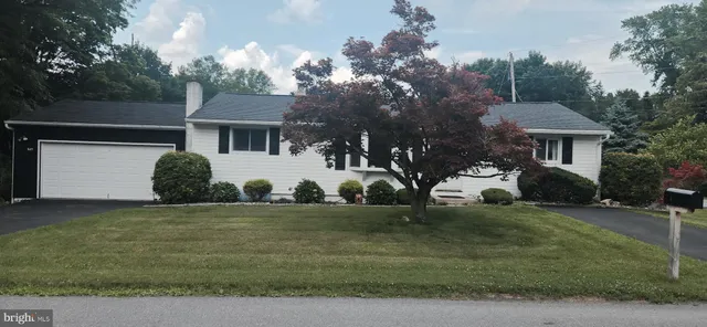 a view of a white house with a yard and large trees