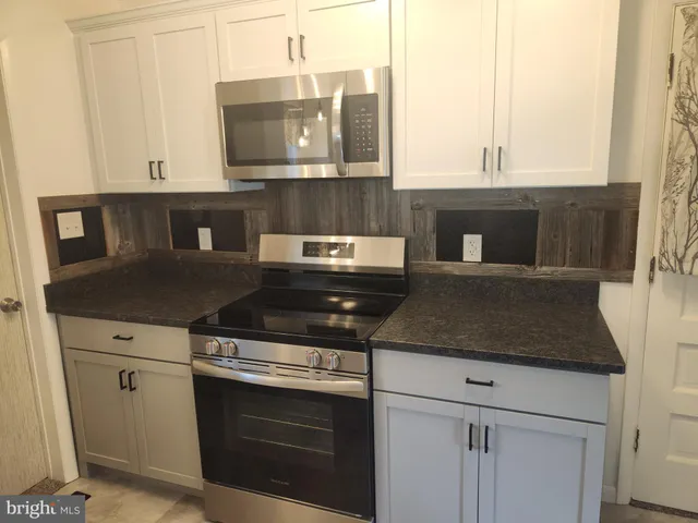 a kitchen with granite countertop a stove and a white cabinets