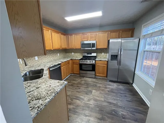 a kitchen with stainless steel appliances granite countertop wooden cabinets a stove a sink and dishwasher