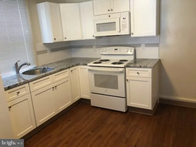 a kitchen with granite countertop white cabinets and white appliances