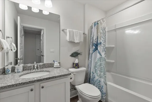 a bathroom with a granite countertop sink a toilet and shower