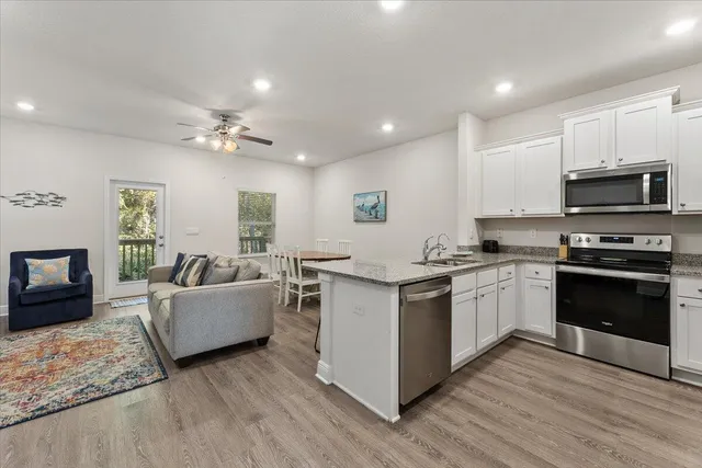 a kitchen with stainless steel appliances granite countertop a stove top oven a sink dishwasher a dining table and chairs with wooden floor