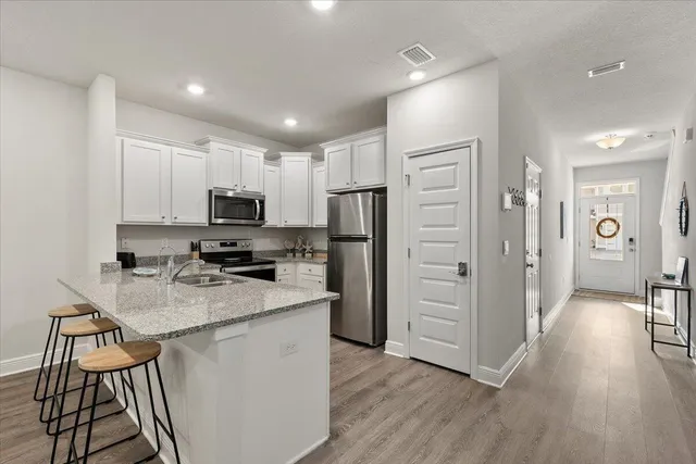 a kitchen with a refrigerator a stove top oven and wooden floor