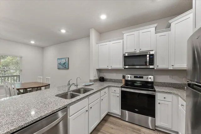 a kitchen with stainless steel appliances granite countertop a sink dishwasher stove and microwave with wooden cabinets