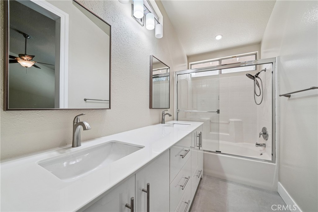 7271 Venosa Place Rancho Cucamonga, CA 91701 - Photo 19 of 32 a bathroom with a sink a mirror a glass door and shower