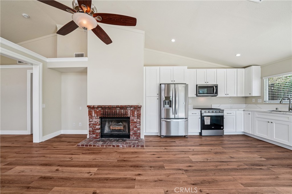7271 Venosa Place Rancho Cucamonga, CA 91701 - Photo 6 of 32 a living room with stainless steel appliances kitchen island a fireplace wooden floor and a ceiling fan