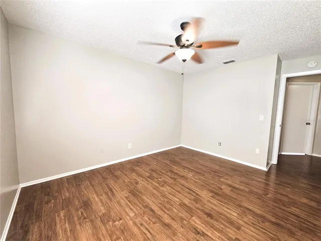an empty room with wooden floor fan and windows