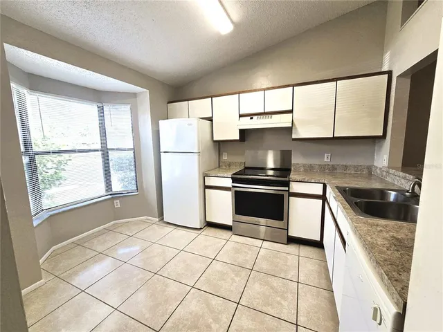 a kitchen with granite countertop a stove a sink and a refrigerator