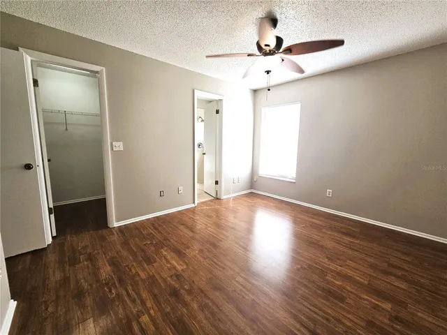an empty room with wooden floor and a ceiling fan