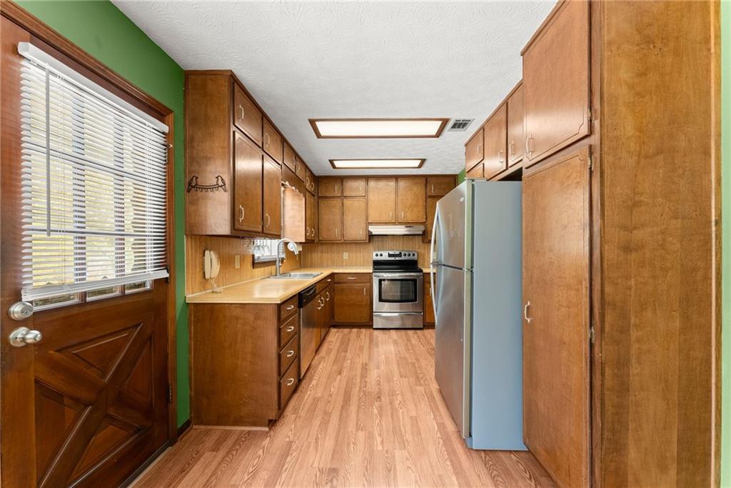 4691 Lucerne Valley Road Southwest Lilburn, GA 30047 - Photo 11 of 55 a kitchen with stainless steel appliances granite countertop a refrigerator a sink dishwasher a stove and white countertops with wooden floor