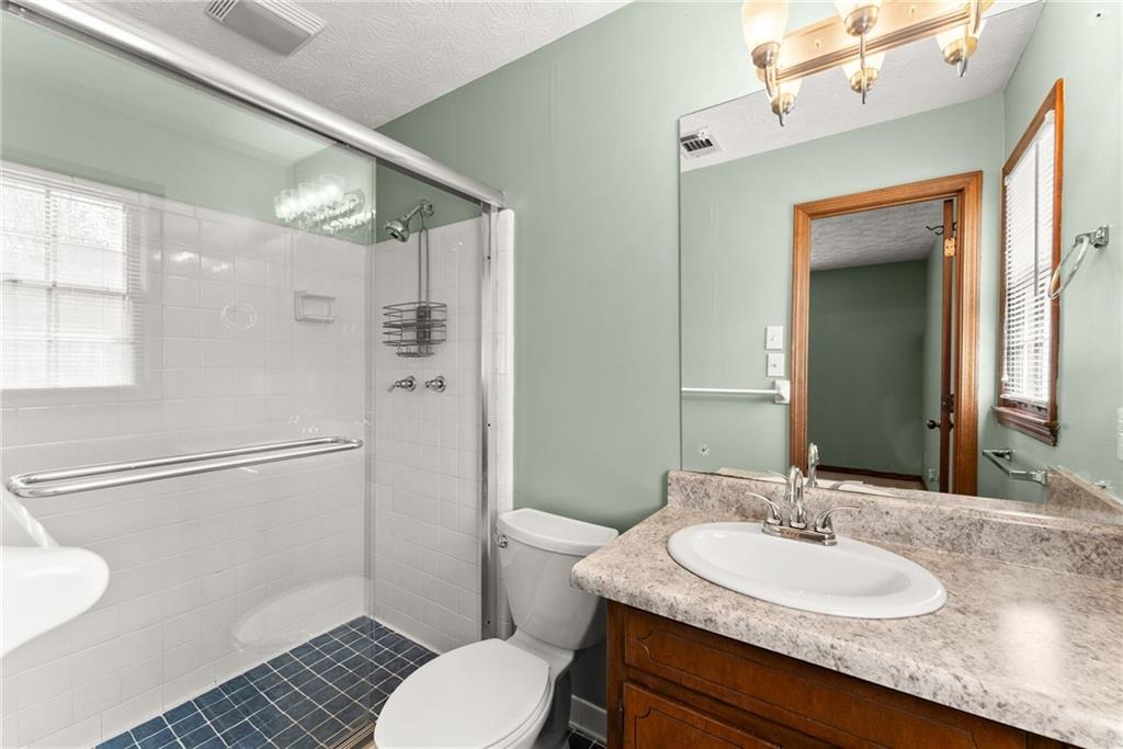 4691 Lucerne Valley Road Southwest Lilburn, GA 30047 - Photo 25 of 55 a bathroom with a granite countertop sink toilet a mirror and shower