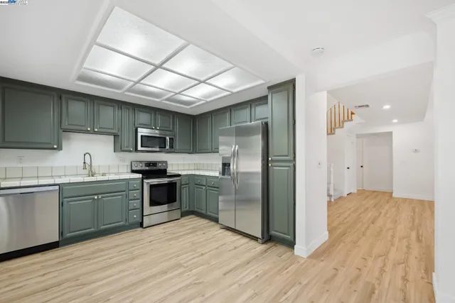 a kitchen with stainless steel appliances granite countertop a refrigerator a sink dishwasher a stove with wooden cabinets and floor