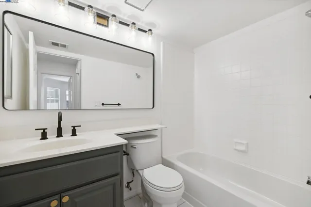 a bathroom with a toilet a sink a mirror and bathtub