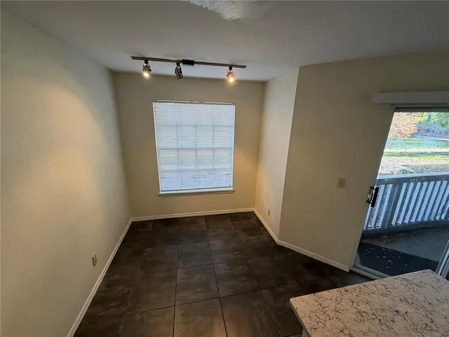 an empty room with wooden floor cabinet and windows
