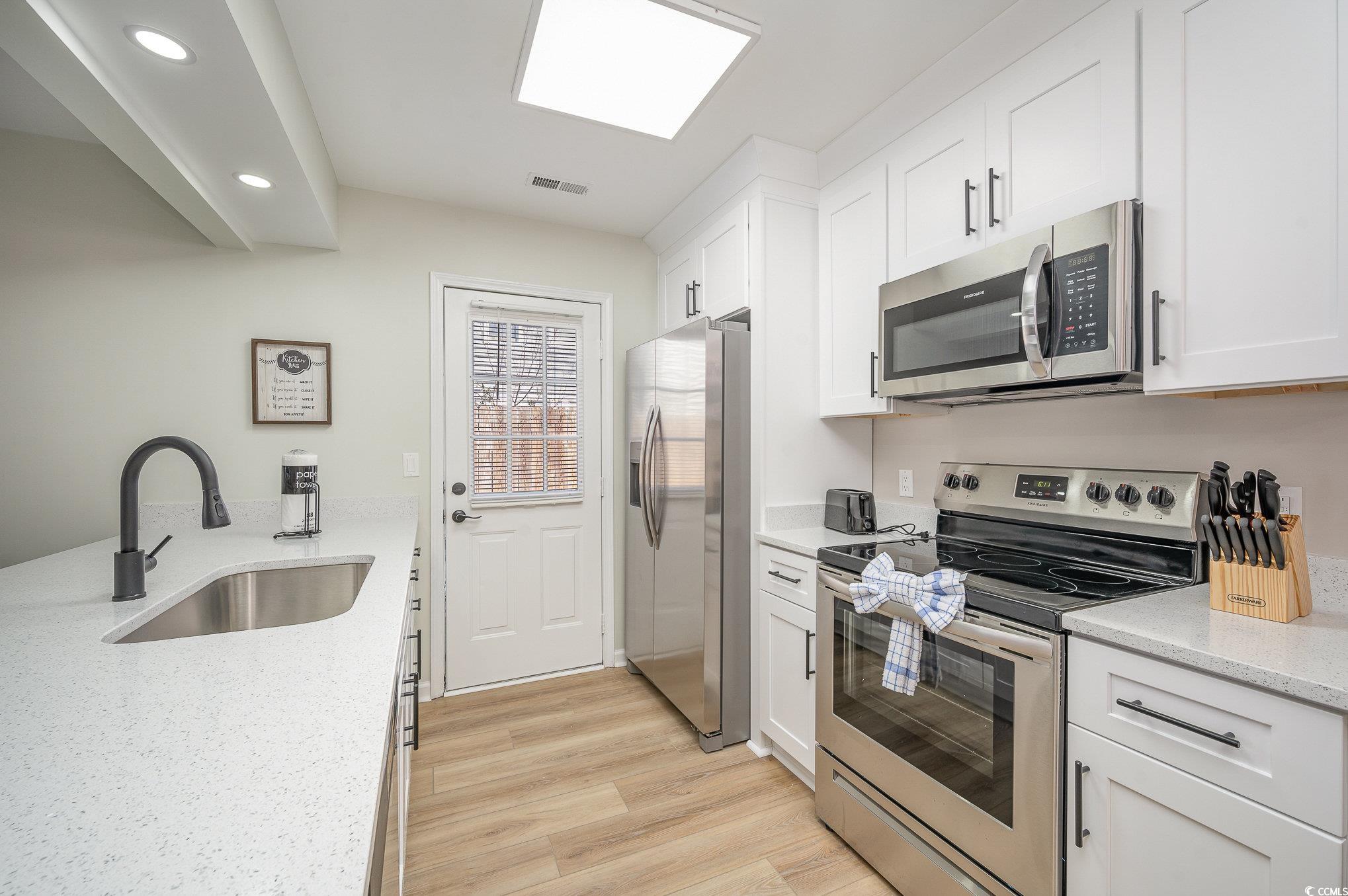 412 27th Avenue North Myrtle Beach, SC 29577 - Photo 7 of 35 Kitchen with appliances with stainless steel finishes, light stone counters, white cabinets, light wood-style floors, and recessed lighting