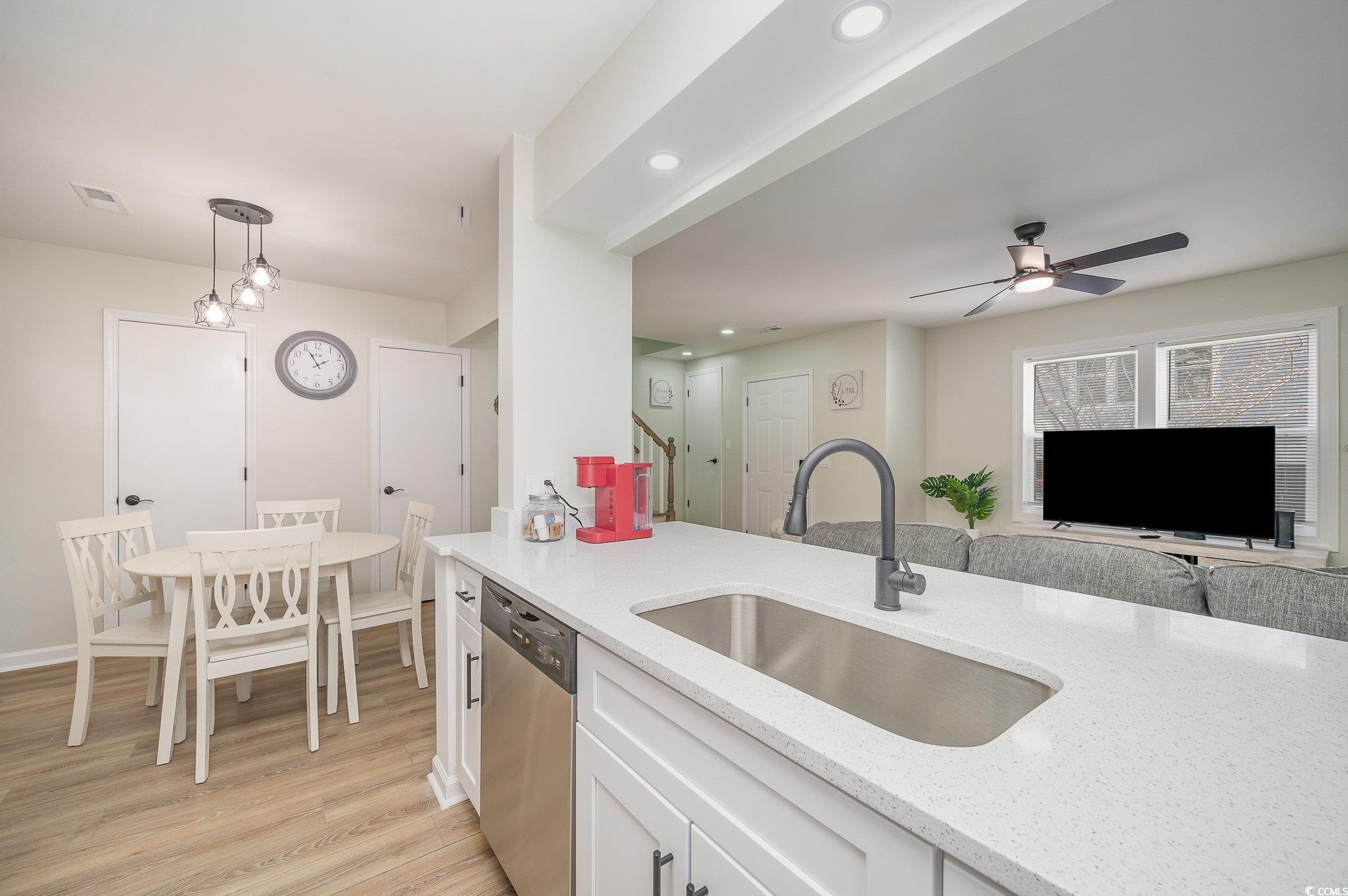412 27th Avenue North Myrtle Beach, SC 29577 - Photo 8 of 35 Kitchen featuring white cabinets, light stone counters, stainless steel dishwasher, hanging light fixtures, and light wood-style floors