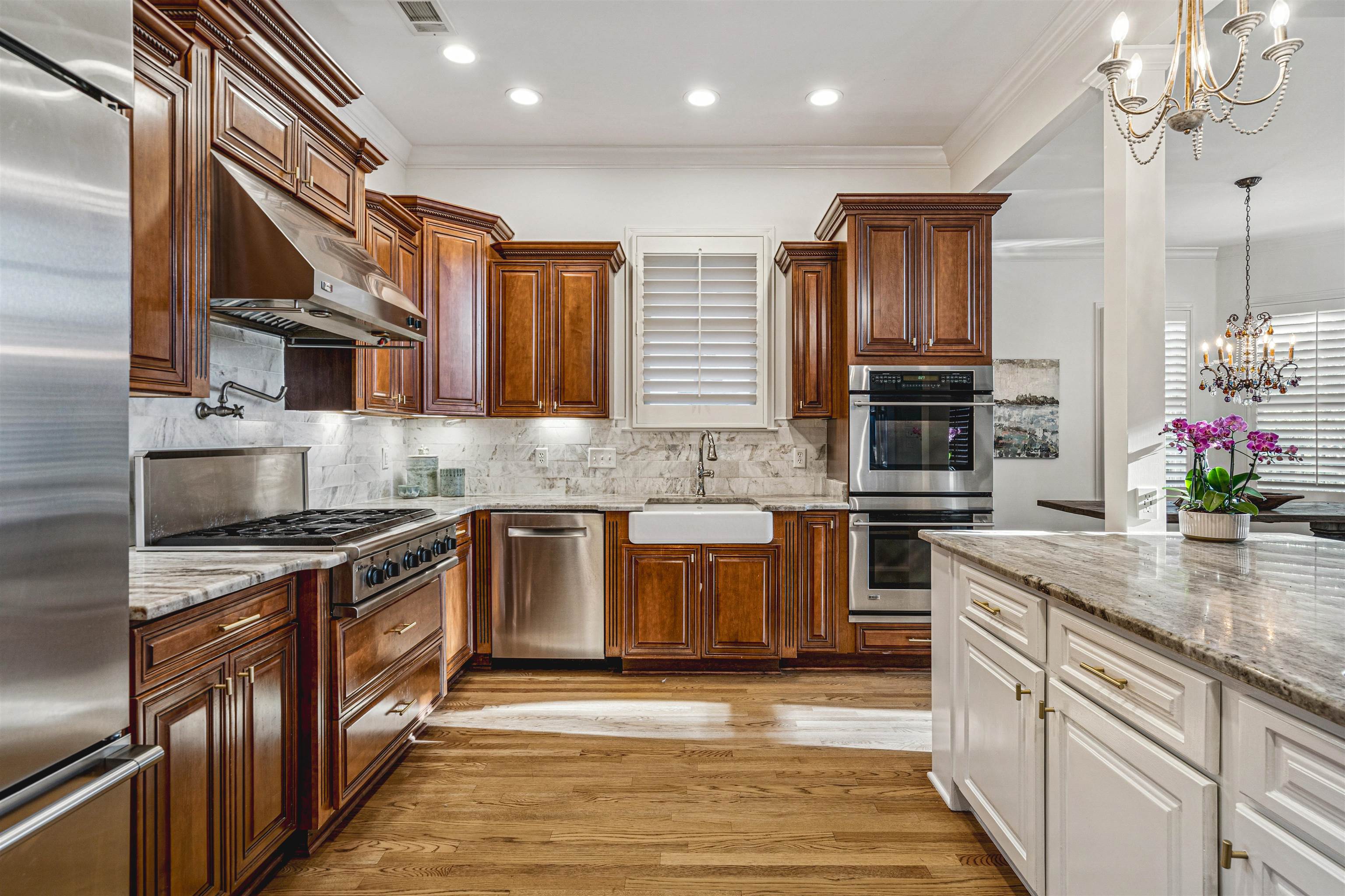 3084 Devonshire Way Germantown, TN 38139 - Photo 15 of 40 Kitchen featuring hanging lights, light stone countertops, two tone color scheme, light wood-style floors, and stainless steel appliances