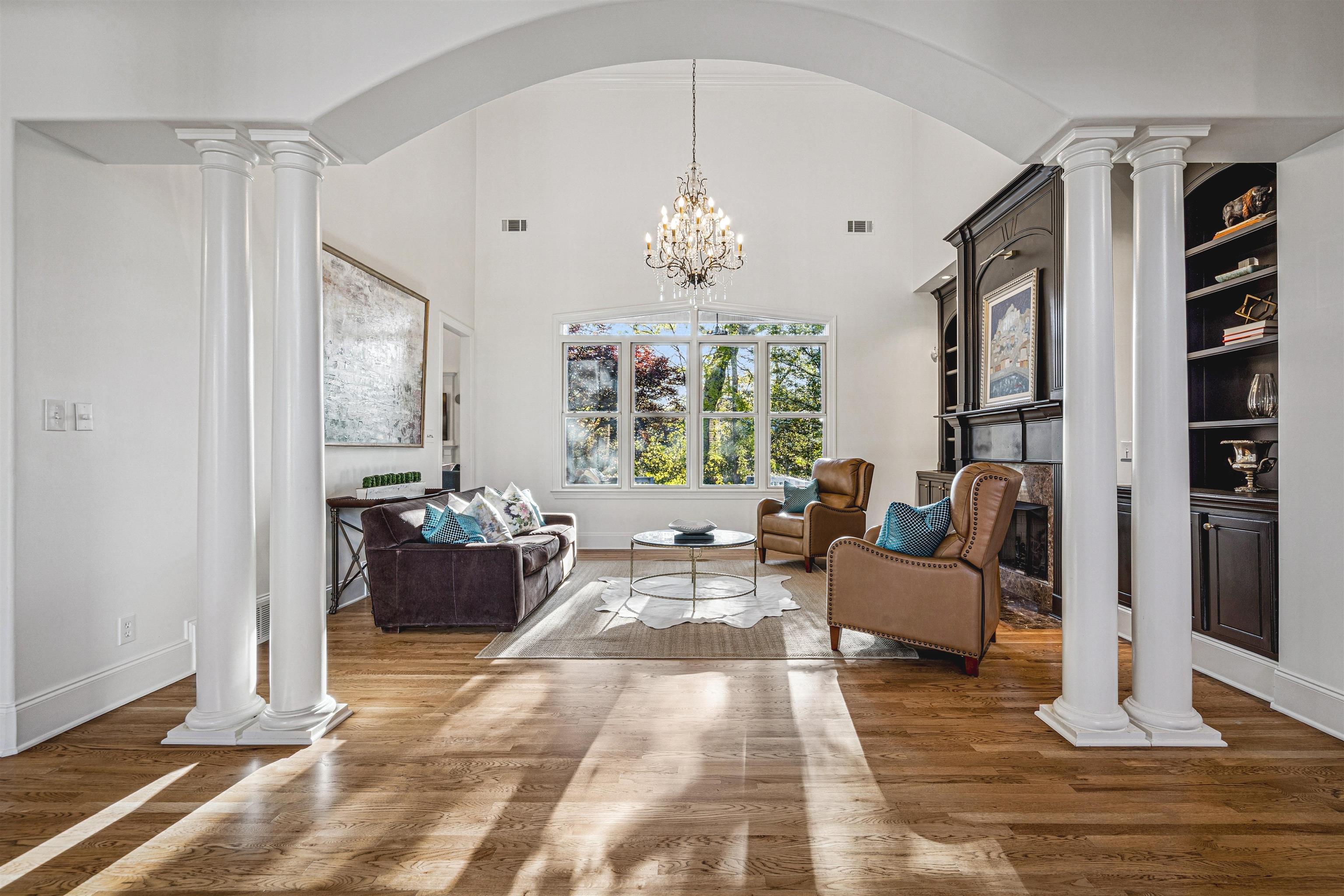 3084 Devonshire Way Germantown, TN 38139 - Photo 7 of 40 Living area with decorative columns, suspended lighting, a glass covered fireplace, wood finished floors, and a high ceiling