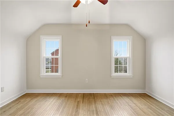 an empty room with wooden floor cabinet and windows