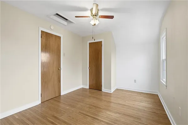 an empty room with wooden floor chandelier fan and closet