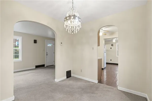 an empty room with chandelier and windows