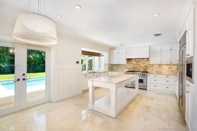 a large kitchen with granite countertop a stove a sink and a refrigerator